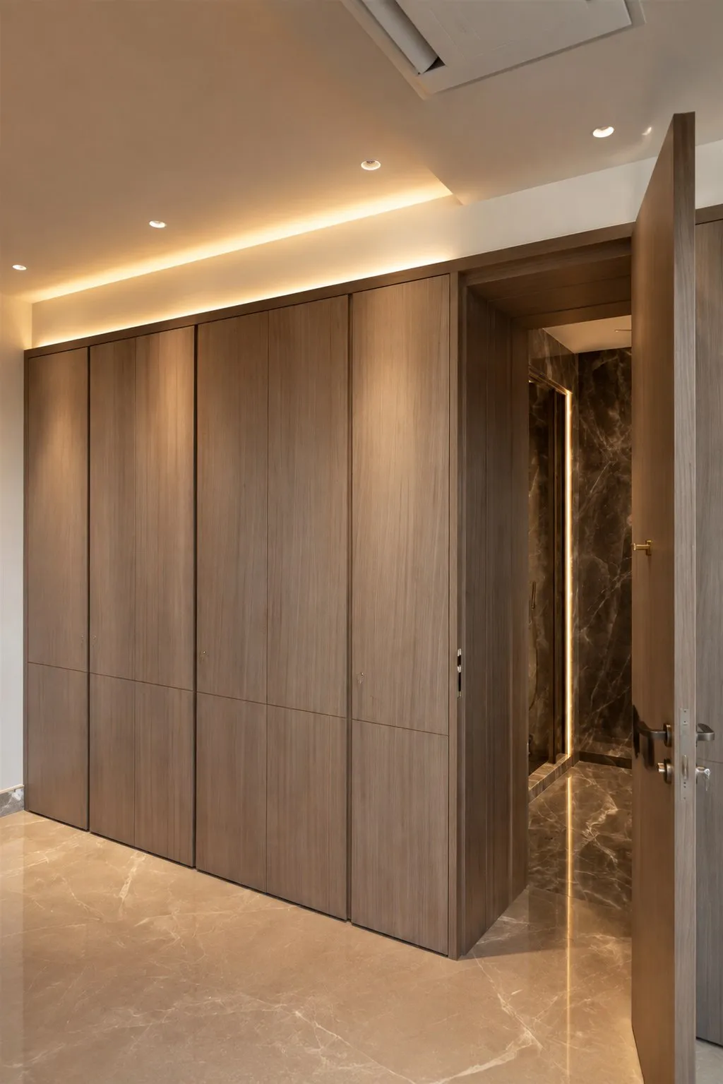 Full-height wardrobe run in light oak, opening to the bathroom